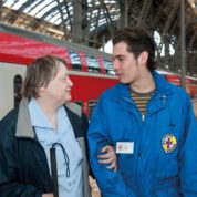 Helfer der Bahnhofsmission mit reisender Frau